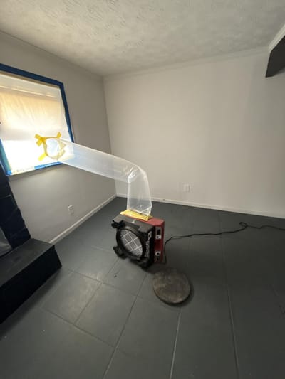 An air scrubber ducted to a window to vent and filter the air in a sealed room
