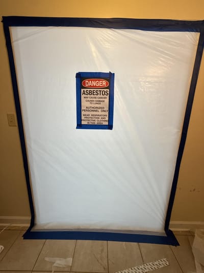 Asbestos warning signage closing off the work area inside the active facility