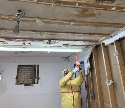 Demolishing the affected ceiling under containment during the abatement