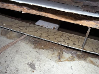 The roughly six-layer floor exposed in cross-section, from ceramic tile down through asbestos vinyl and hardwood