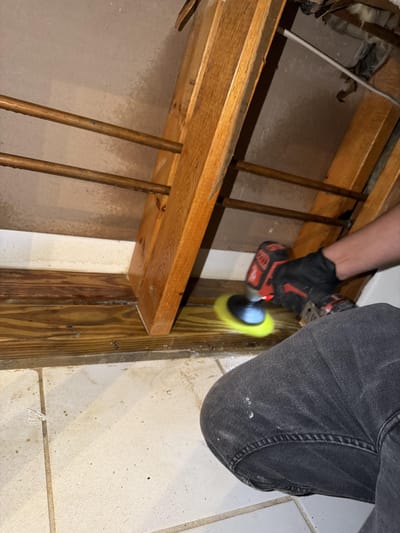 Scrubbing the studs and sill plate with a drill brush during the cleaning sequence