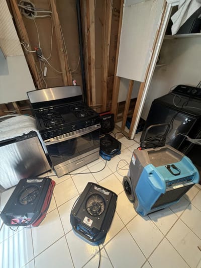Air movers and a dehumidifier running in the gutted kitchen to dry the structure