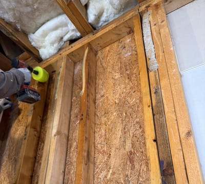 Scrubbing the exposed garage framing clean with a drill brush