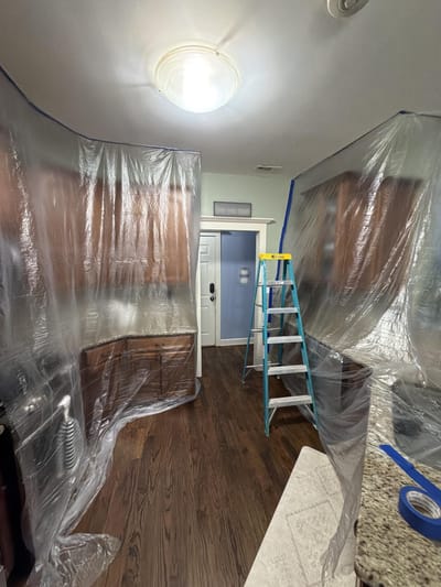 The kitchen cabinets and surfaces draped in heavy plastic to seal the area off before work