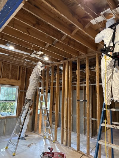 Crew in protective gear HEPA vacuuming and wiping down the exposed framing