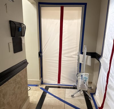 A poly containment barrier with a zipper door sealing off the end-of-hall office